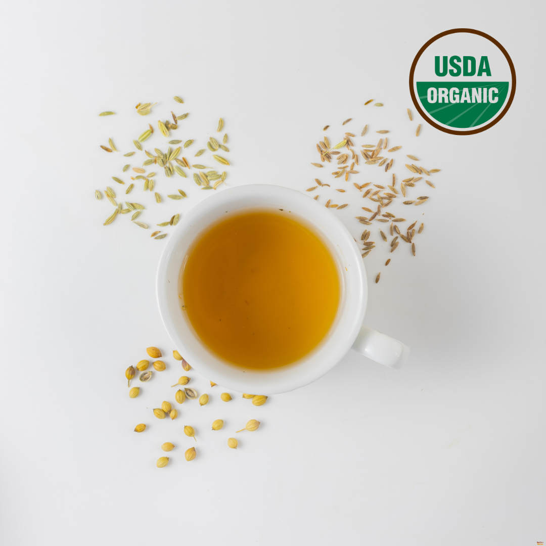 Cumin, Coriander, Fennel tea for gas and bloating is brewed in a white cup. Around the cup are fennel seeds for gas, organic cumin for detox and organic coriander for acidity. This Ayurvedic CCF tea is certified organic as indicated by USDA organic logo on the right top corner.