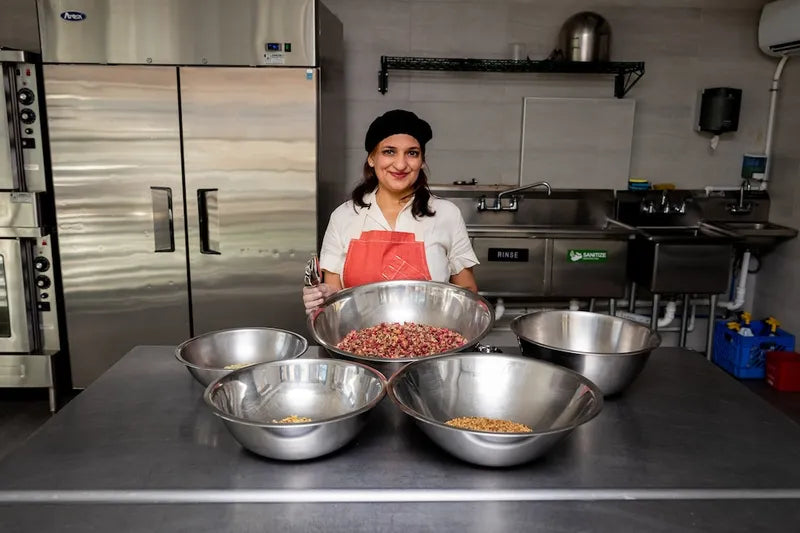 Divya, AyurSome Wellness founder, preparing rose and fennel tea blend ingredients in a commercial kitchen