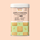 A square cookie tin of Simply Einkorn cookies by AyurSome Wellness. The tin is of wheat and cardamom color. The background is of whole wheat color as well. The cookie tins has pictures of the vegan einkorn cookies that are packed in the tin. 